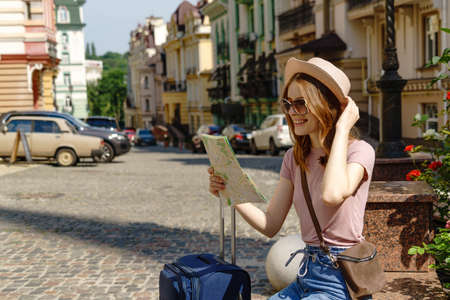 Beautiful Young Woman tourist Pleasant with city map and suitcase in the City Center