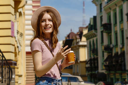 Beautiful Young Woman tourist with takeout coffee in the City Center talking on the phone