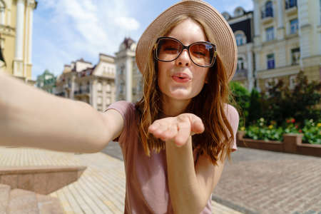 Pretty young woman in glasses making selfie at city center