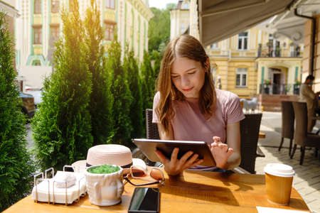 young woman using tablet pc in a cafe on a summer terrace