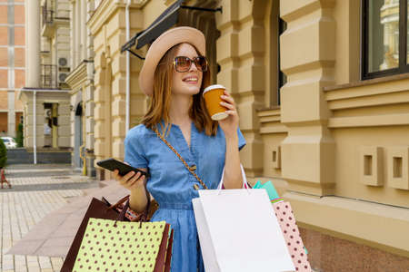 Young Woman with shopping bags walking in a city at summer dayの写真素材