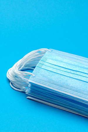 Stack of Disposable blue medical face masks on blue background