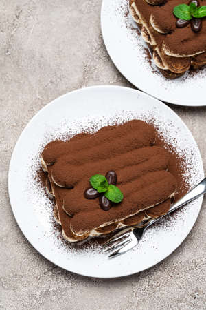 Two portions of Classic tiramisu dessert on ceramic plate on concrete backgroundの写真素材