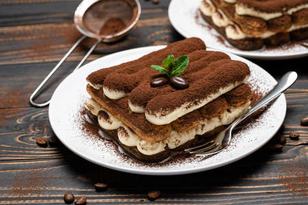 Two portions of Classic tiramisu dessert on ceramic plate on wooden backgroundの写真素材