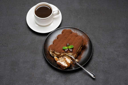 portion of Classic tiramisu dessert and cup of fresh espresso coffee on concrete background