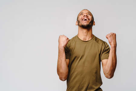 Young African-American man yes win gesturing over light grey backgroundの写真素材