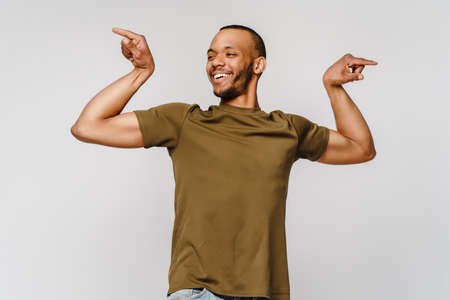 Close up portrait of a happy african american man wearing t-shirt flexing bicep arm muscleの写真素材