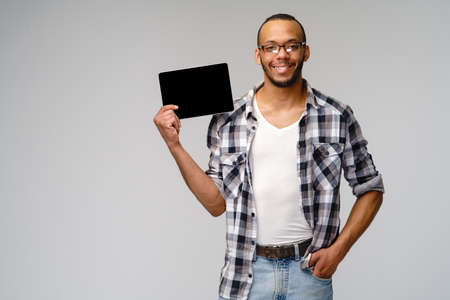 Portrait of a young african american man wearing green t-shirt holding tablet pc pad