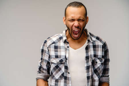 Photo of emotional screaming young african-american man standing over light grey backgroundの写真素材