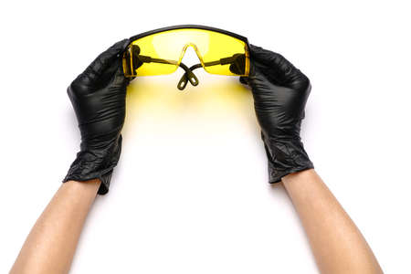 hands with medical latex gloves holding protective goggles on white backgroundの写真素材