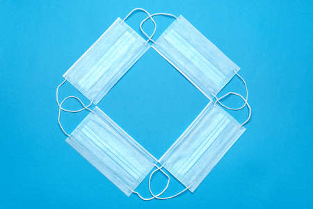 Stack of Disposable blue medical face masks on blue background