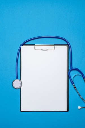 Stethoscope and clipped board with paper over blue backgroundの写真素材