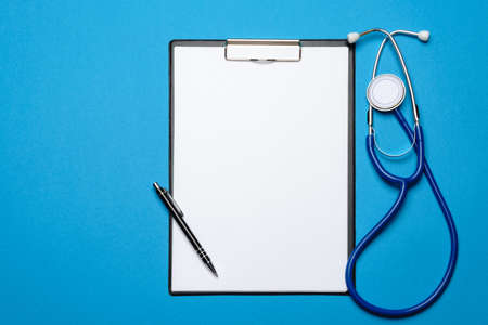 Stethoscope and clipboard with paper over blue backgroundの写真素材