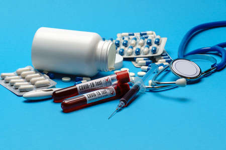 Stethoscope, syringe, thermometer, blood test tube and can of pills on blue background top view with...
