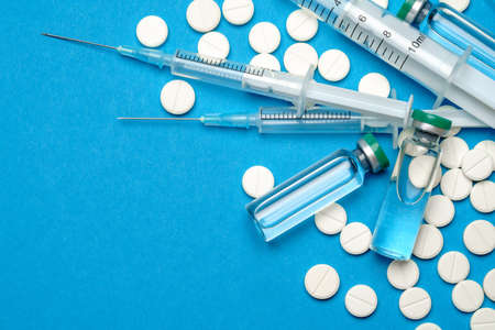 Top view of Pills, Syringe And Ampoule With Vaccination On blue background with copy space