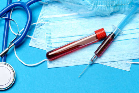 Medical lab concept - Covid-19 blood sample in test tube and syringe on blue background