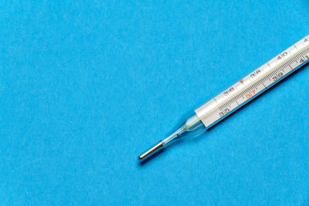 mercury thermometer on blue background - top view with copy space