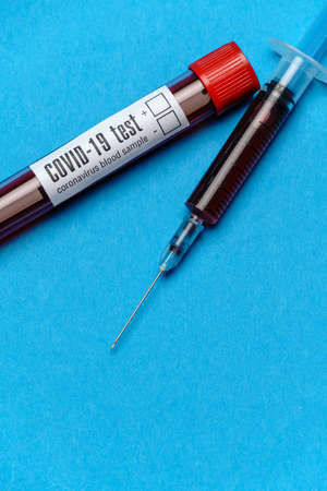 Syringe And Plastic Test Tube With Blood Sample over blue background with copyspace