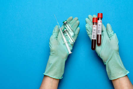 lab technician assistant or doctor wearing rubber or latex gloves holding an ampoule with medicine...