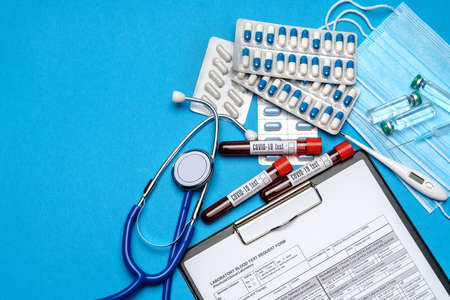 Clipboard with paper blank form with medical tools on blue background with cope space.