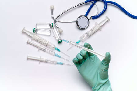 lab technician assistant holding syringe over light grey or white background with medical ampoule...