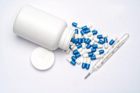 Medications capsules in a bottle and thermometer on light grey backgroundの写真素材