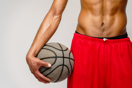 Muscular african american sportsman playing basketball shitless over light grey backgroundの写真素材