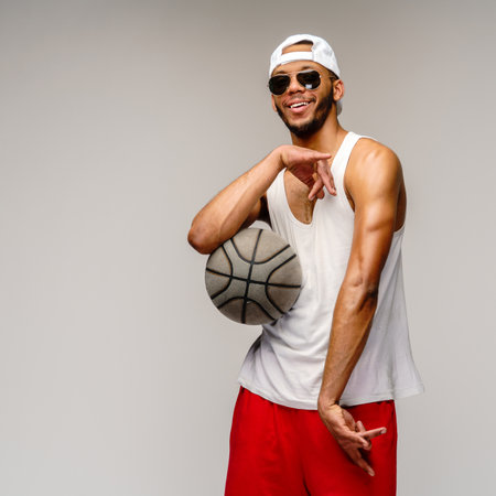 Muscular african american sportsman playing basketball over light grey backgroundの写真素材
