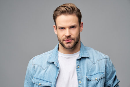 Portrait of young handsome caucasian man in jeans shirt over light backgroundの写真素材