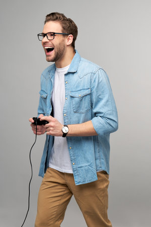 young man in casual jeans shirt holding joystick or gamepad playing gameの写真素材