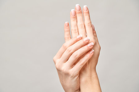 Beautiful Female Hands with French manicure over light grey backgroundの写真素材