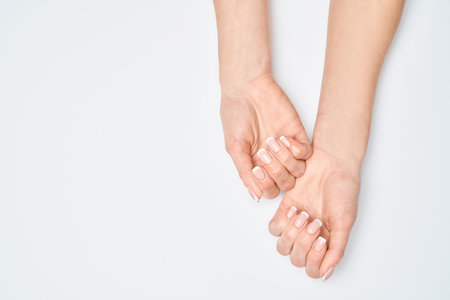 Beautiful Female Hands with French manicure over light grey backgroundの写真素材