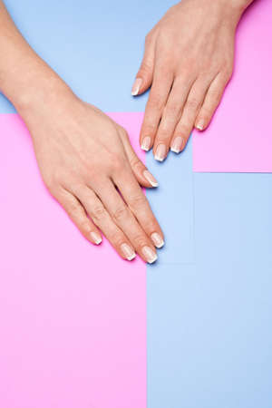 Beautiful Female Hands with French manicure over colorful paper backgroundの写真素材