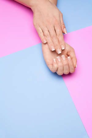 Beautiful Female Hands with French manicure over colorful paper backgroundの写真素材