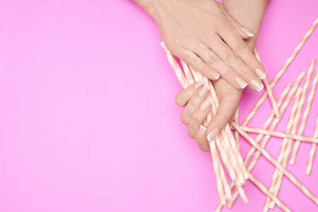 Beautiful Female Hands with French manicure over colorful paper backgroundの写真素材