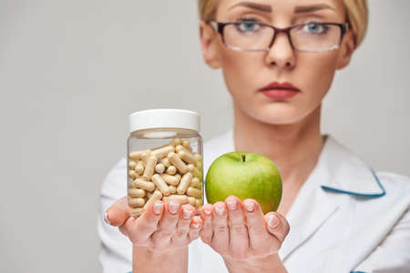 nutritionist doctor healthy lifestyle concept - holding organic fresh green apple and can of vitamin...