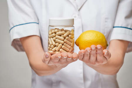nutritionist doctor healthy lifestyle concept - holding fresh organic lemon fruit and vitamin...