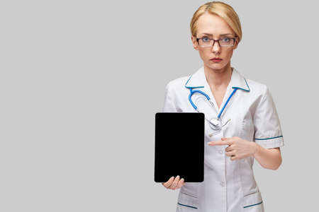 beautiful female doctor holding tablet pc pad isolated on grey background
