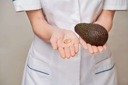 Health care and diet concept - doctor nutritionist or cardiologist holding fish oil in capsules for...