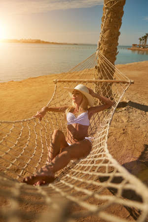 Travel and vacation concept - Woman relaxing on hammock on the beachの写真素材