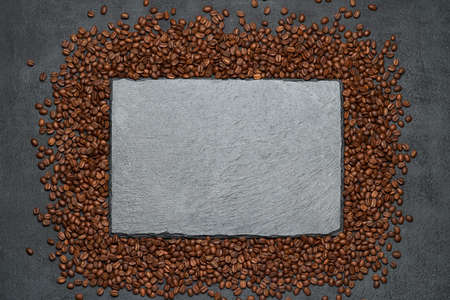 Background or texture made of roasted brown coffee beans and stone serving board