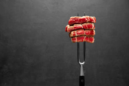 Studio shot of slices of steak on a meat forkの写真素材