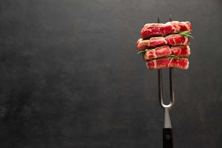Studio shot of slices of steak on a meat forkの写真素材