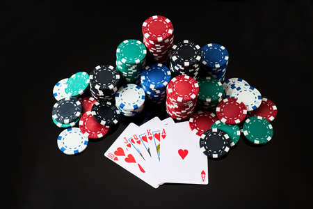 Stack of Casino gambling chips and cards isolated on black reflective background