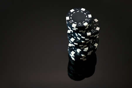 Stack of Casino gambling chips isolated on black reflective background