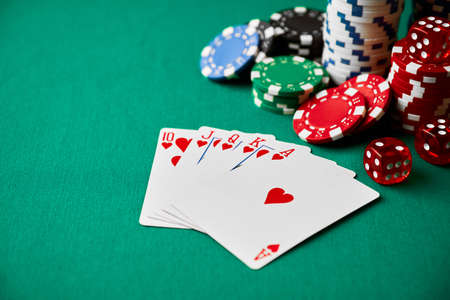 Casino chips, playing cards and dices on green fabric table