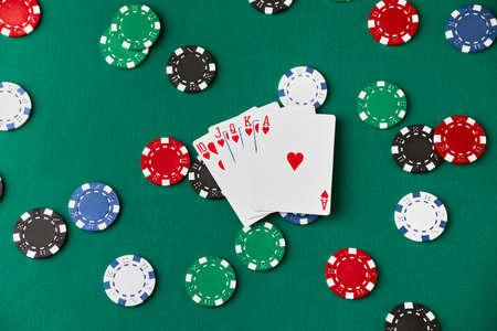 Casino pocker chips and playing cards on green fabric table