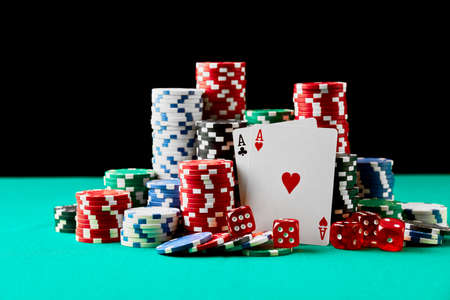 Casino chips, playing cards and dices on green fabric table