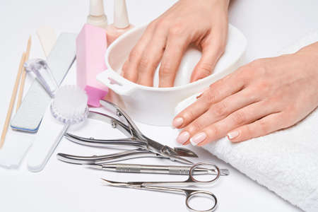 Beautiful Female Hands with French manicure over light grey backgroundの写真素材