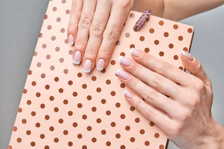 Beautiful Female Hands with French manicure over light grey backgroundの写真素材
